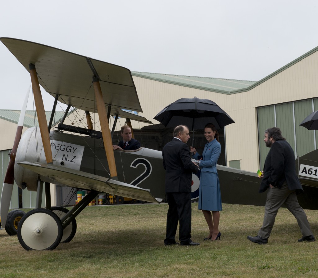 The Duke sits in a replica WWI plane while the Duchess and Peter Jackson look on